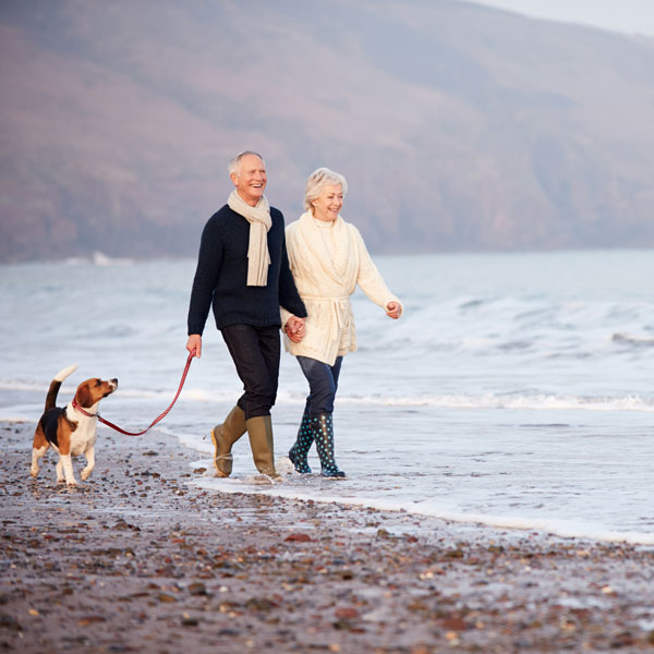 Retired couple walking their dog at North Wales beach